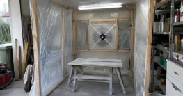 Selbst gebaute Lackierkabine aus Holzlatten und Folie mit Ventilator in der Rückwand